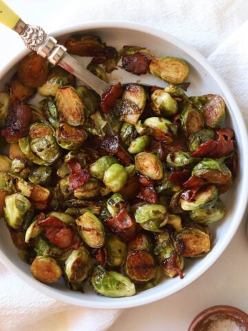 Balsamic Glaze Brussels sprouts in white bowl with serving spoon.