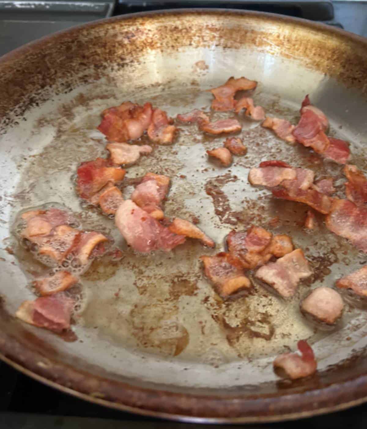 Bacon sautéing in pan.