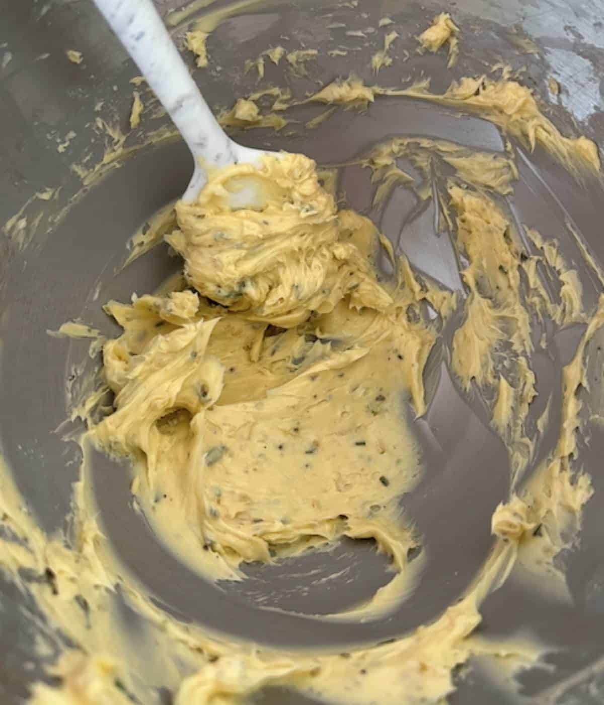Whipped garlic rosemary butter in mixing bowl.