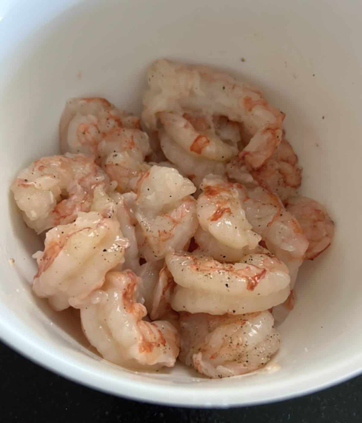 Argentina shrimp in white bowl seasoned with salt and pepper.