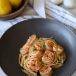 Shrimp scampi with linguine and white wine sauce in gray bowl.