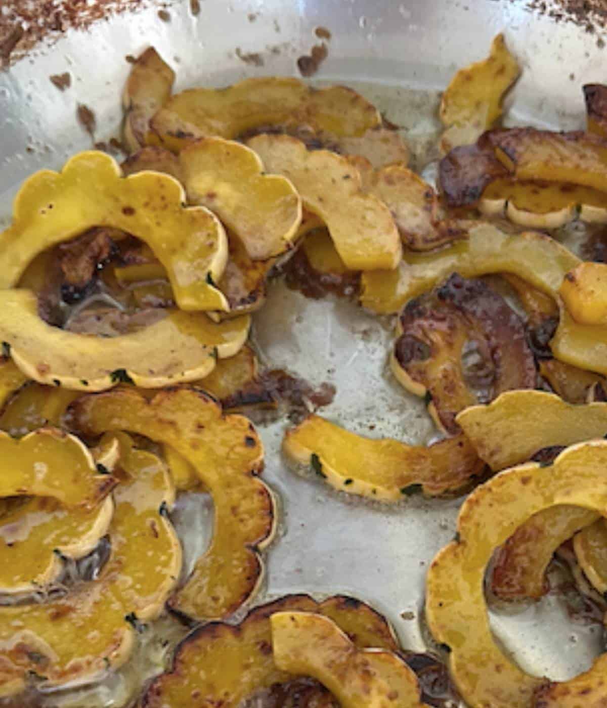 Delicata squash tossed in butter sauce in skillet.