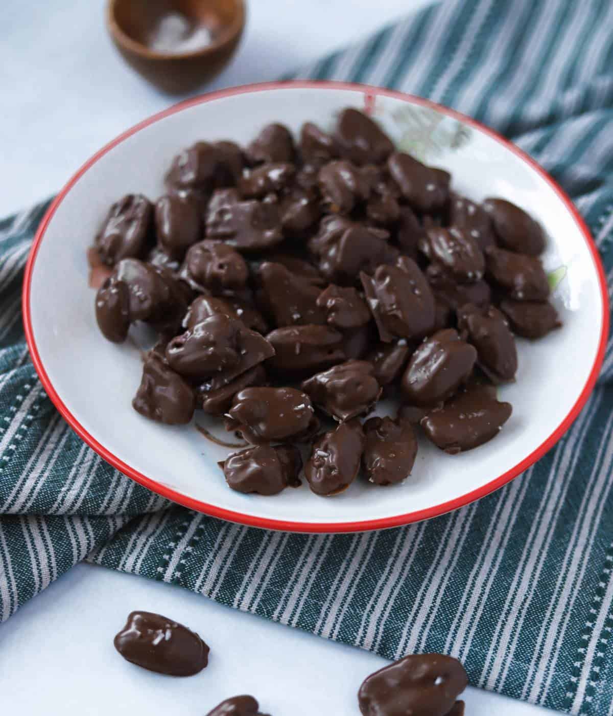 Chocolate covered pecans with salt on plate.