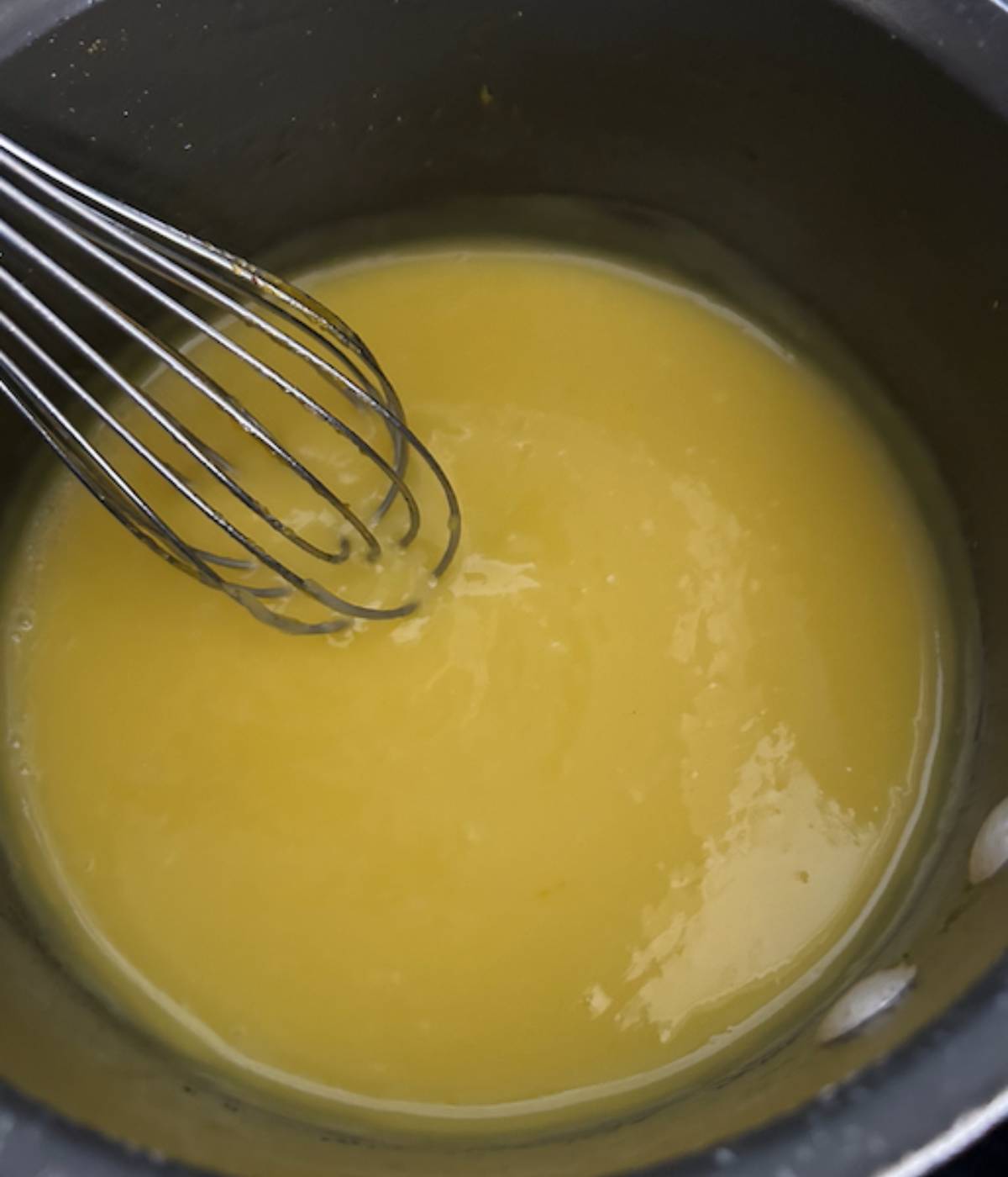 Lemon curd in pan with whisk.
