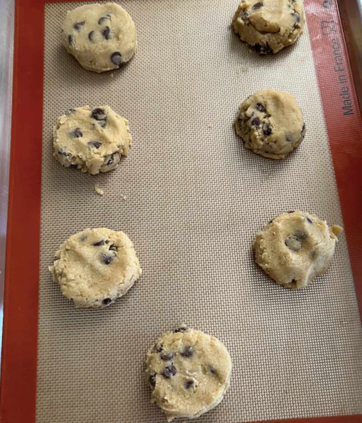 Chocolate chip cookies ready to bake on silpat lined cookie sheet.