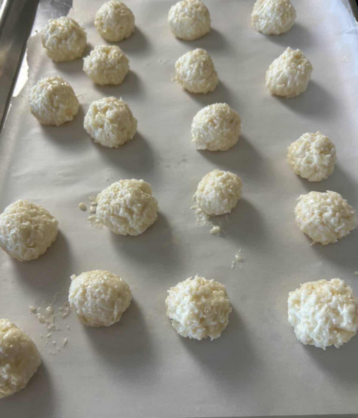 Coconut mixture rolled into balls on parchment lined cookie sheet.