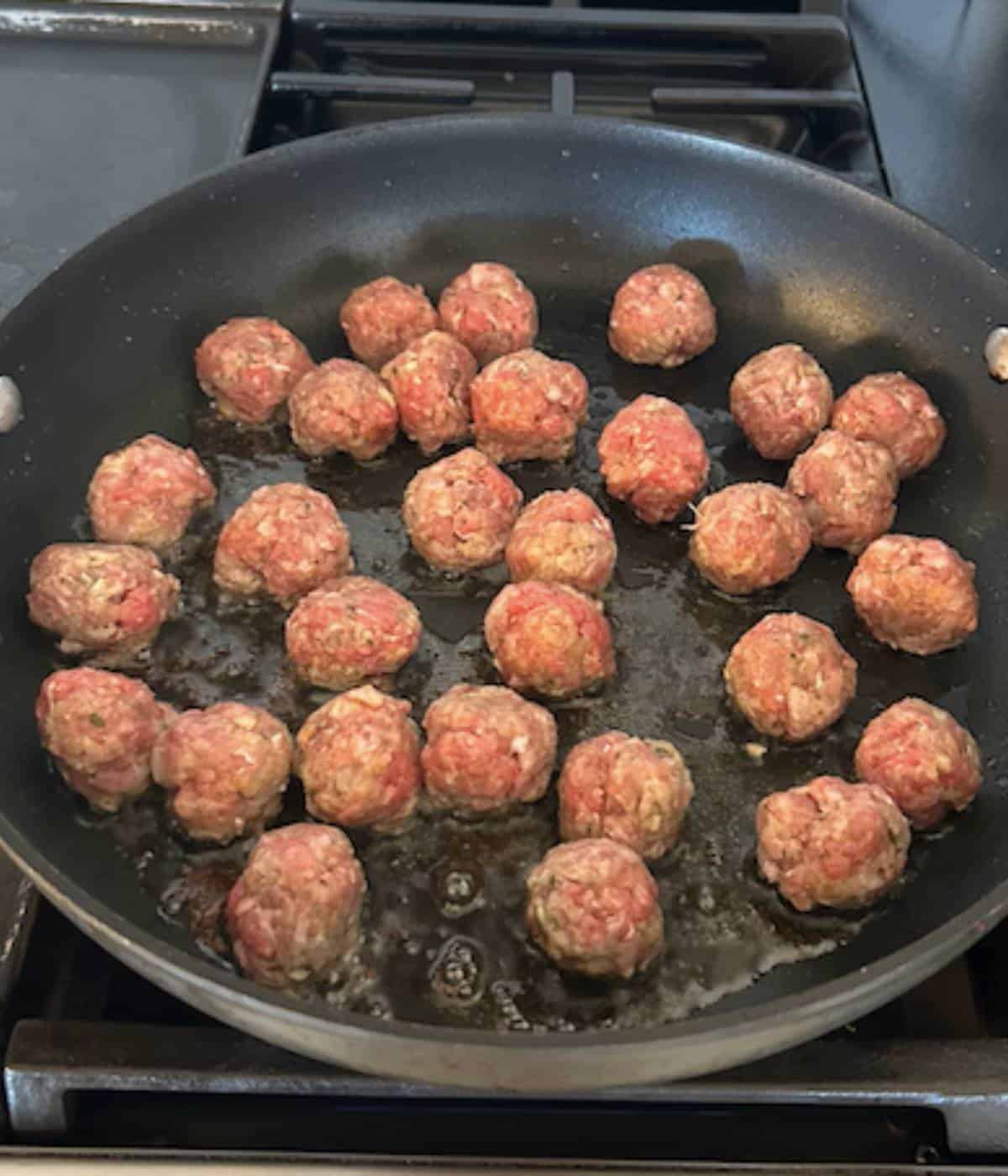 Mini meatballs cooking in skillet.