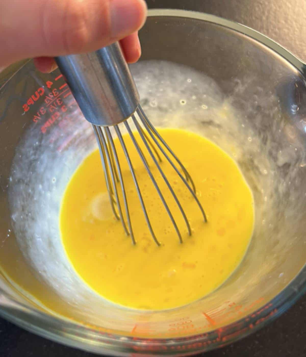 Eggs and milk whisked together in pyrex dish.