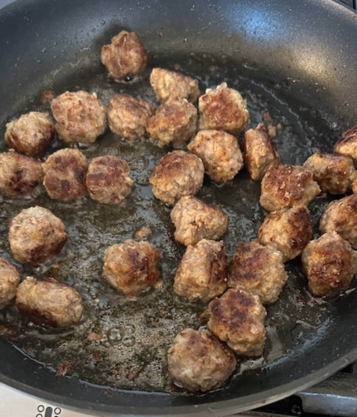 Small meatballs pan frying in skillet.