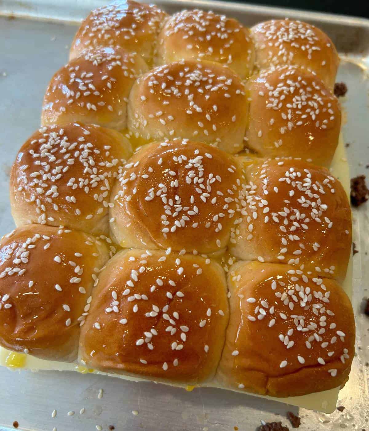 Hawaiian rolls topped with melted butter and sesame seeds.