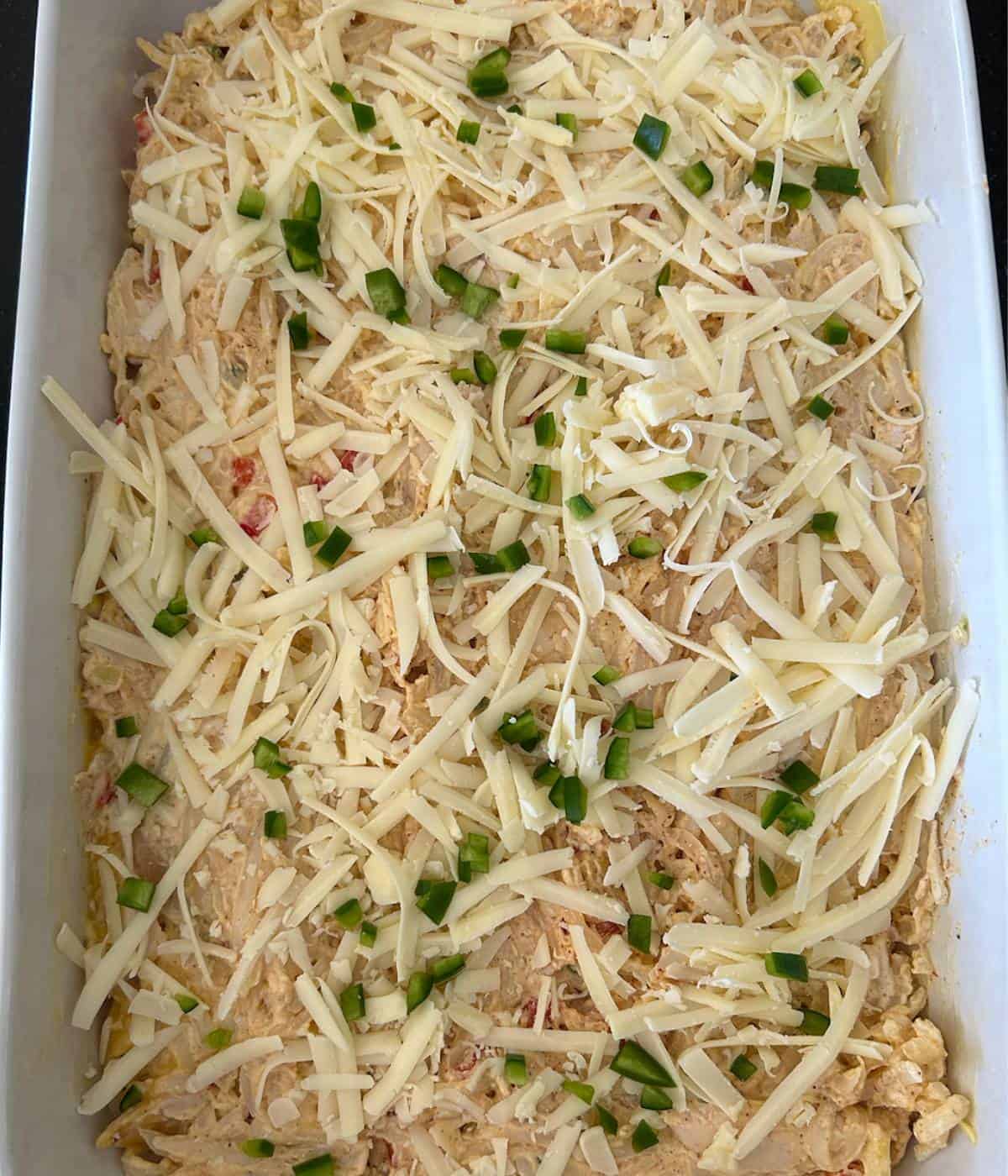 Casserole in 9x13 dish topped with cheese and jalapeรฑo.