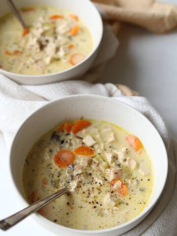 Two bowls of chicken and rice soup with mushrooms and carrot.