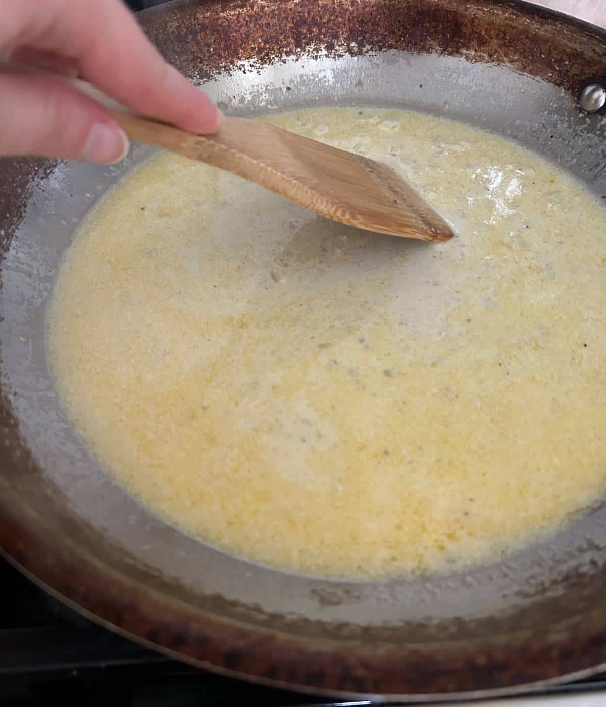 Adding heavy cream to lemon sauce in skillet.