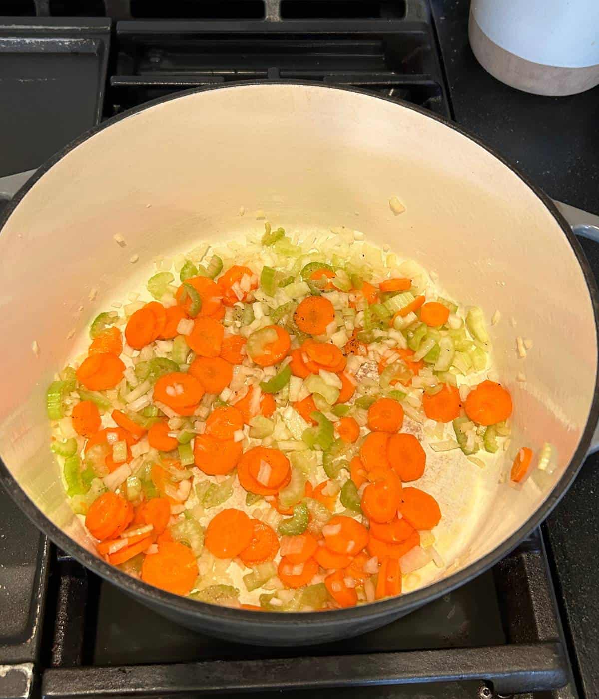 Cooking mirepoix of carrot, celery and onion in pot.