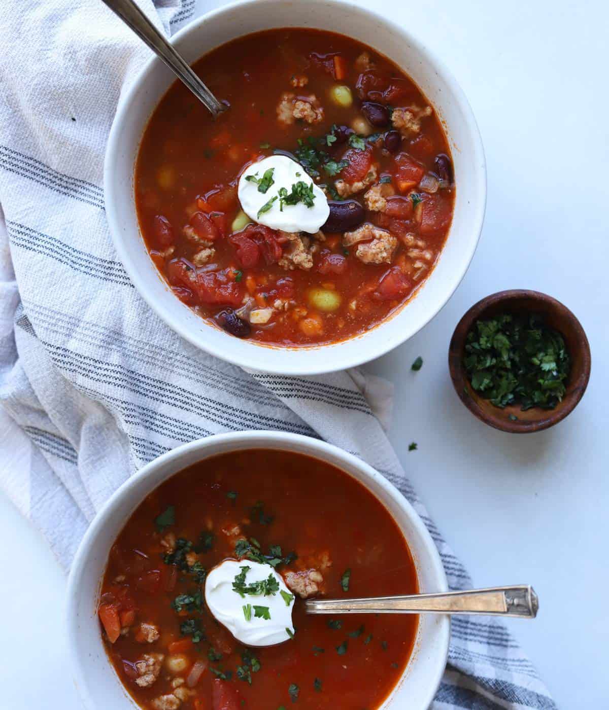 Two bowls of turkey chili topped with sour cream.