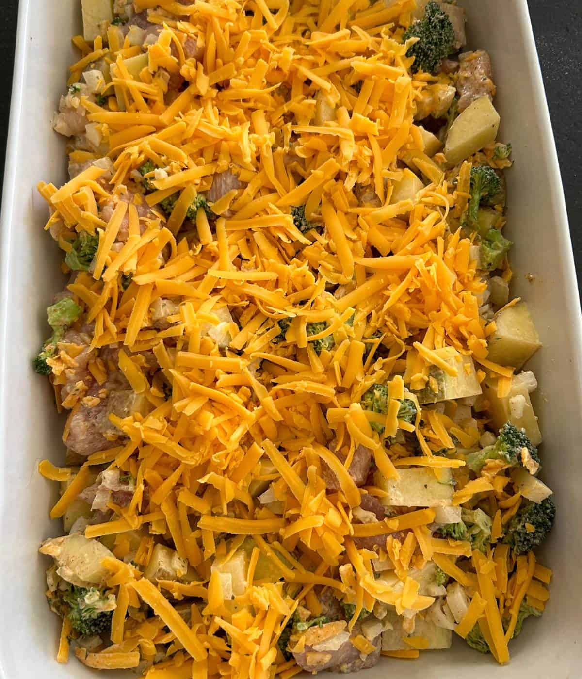 Casserole in dish topped with cheddar cheese.
