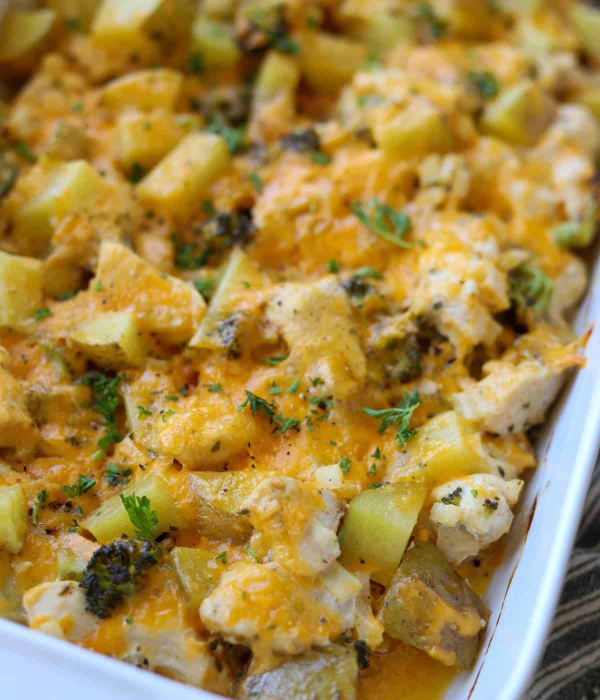 Chicken potato broccoli bake in casserole dish topped with cheese.