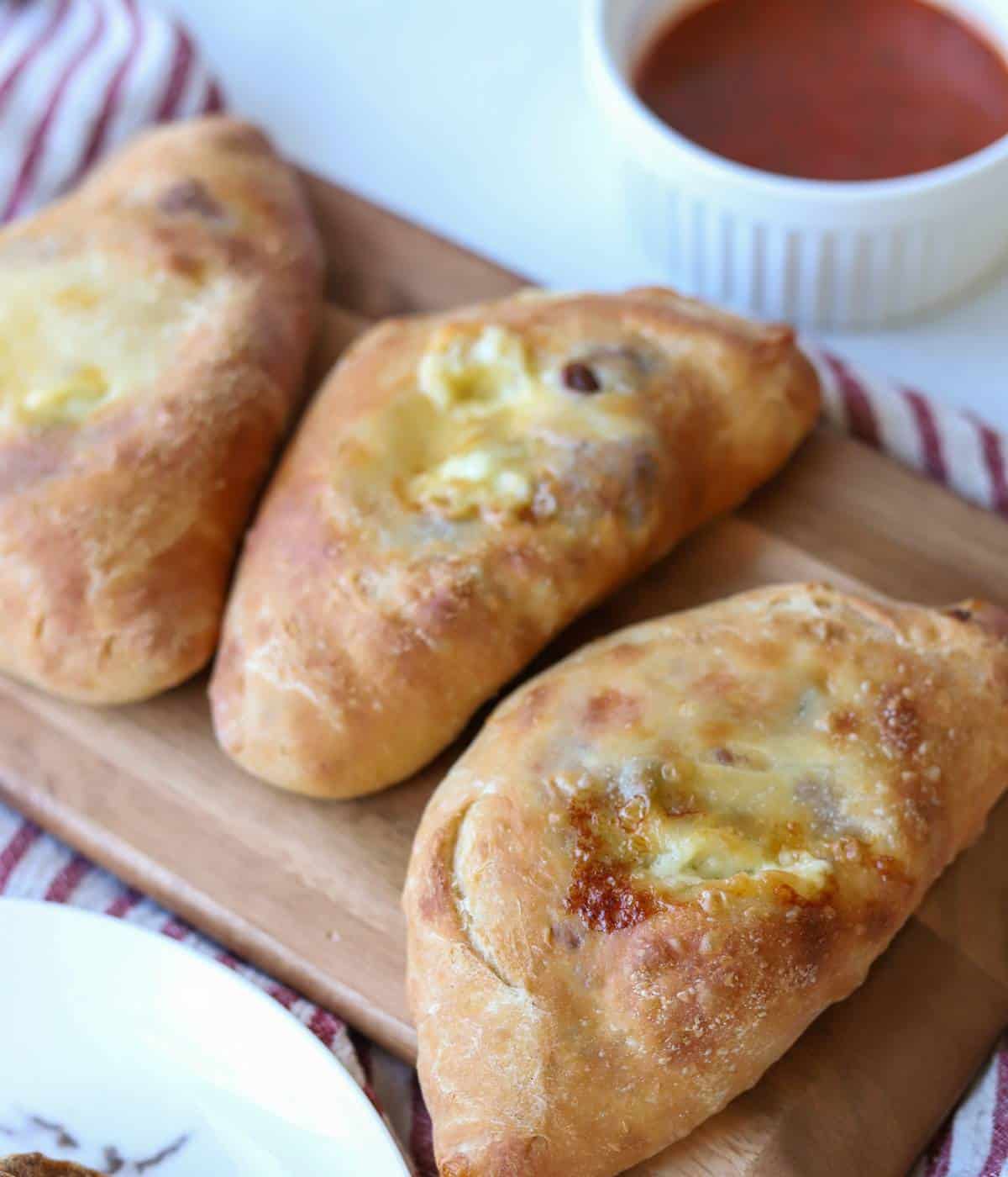 Steak and Cheese calzones on serving tray with marinara.