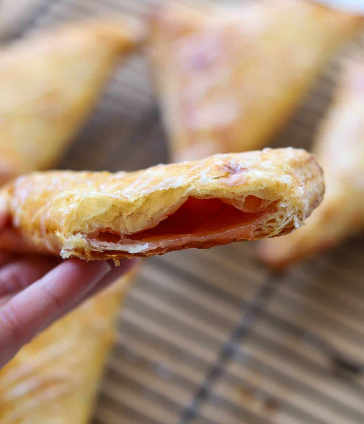 Hand holding pastry with strawberry filling.