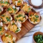 Wonton cups filled with buffalo chicken and green onion on platter.