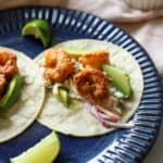 Shrimp tacos with jalapeño slaw, avocado and lime on corn tortilla.