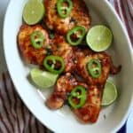 Chicken thighs with bbq sauce topped with jalapeño and limes.