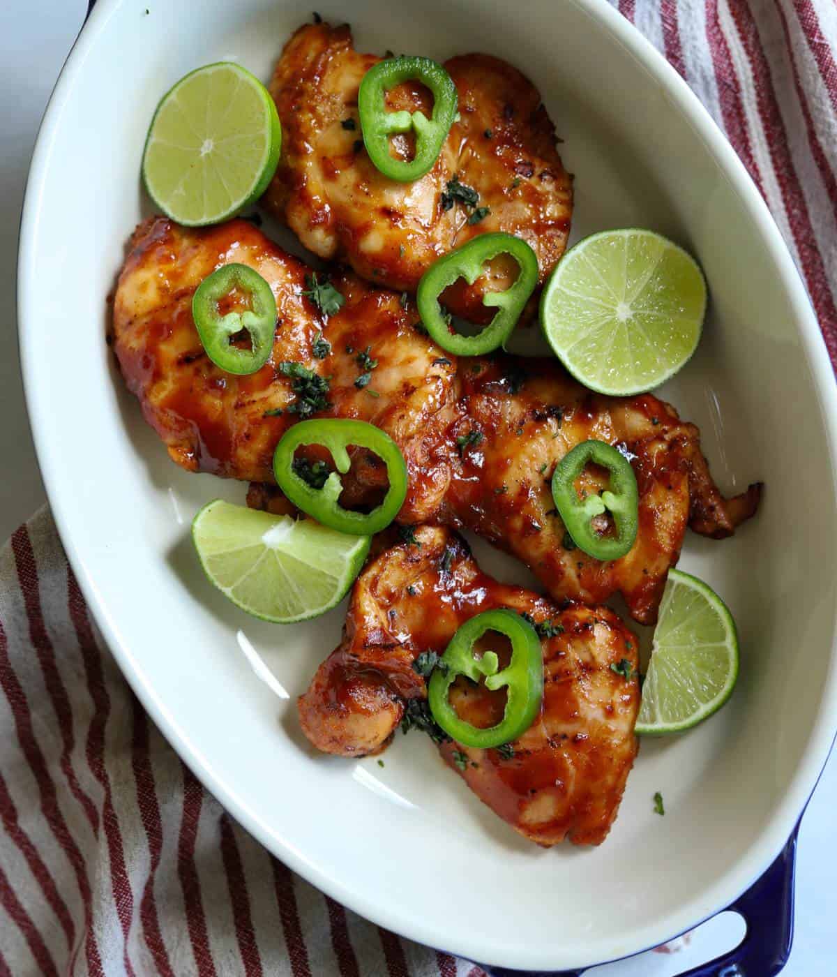 Chicken thighs with bbq sauce topped with jalapeño and limes. 