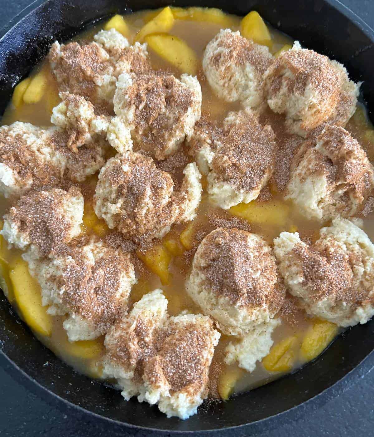 Peaches in skillet topped with biscuit topping.