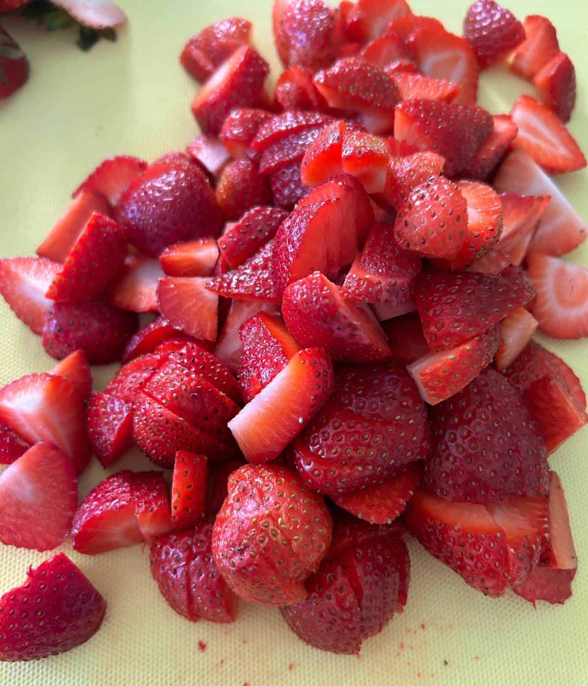 Sliced strawberries on cutting board.