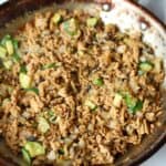 Ground chicken stir fry with sesame seeds in pan.