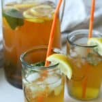 Two glasses of mint tea with pitcher in back.