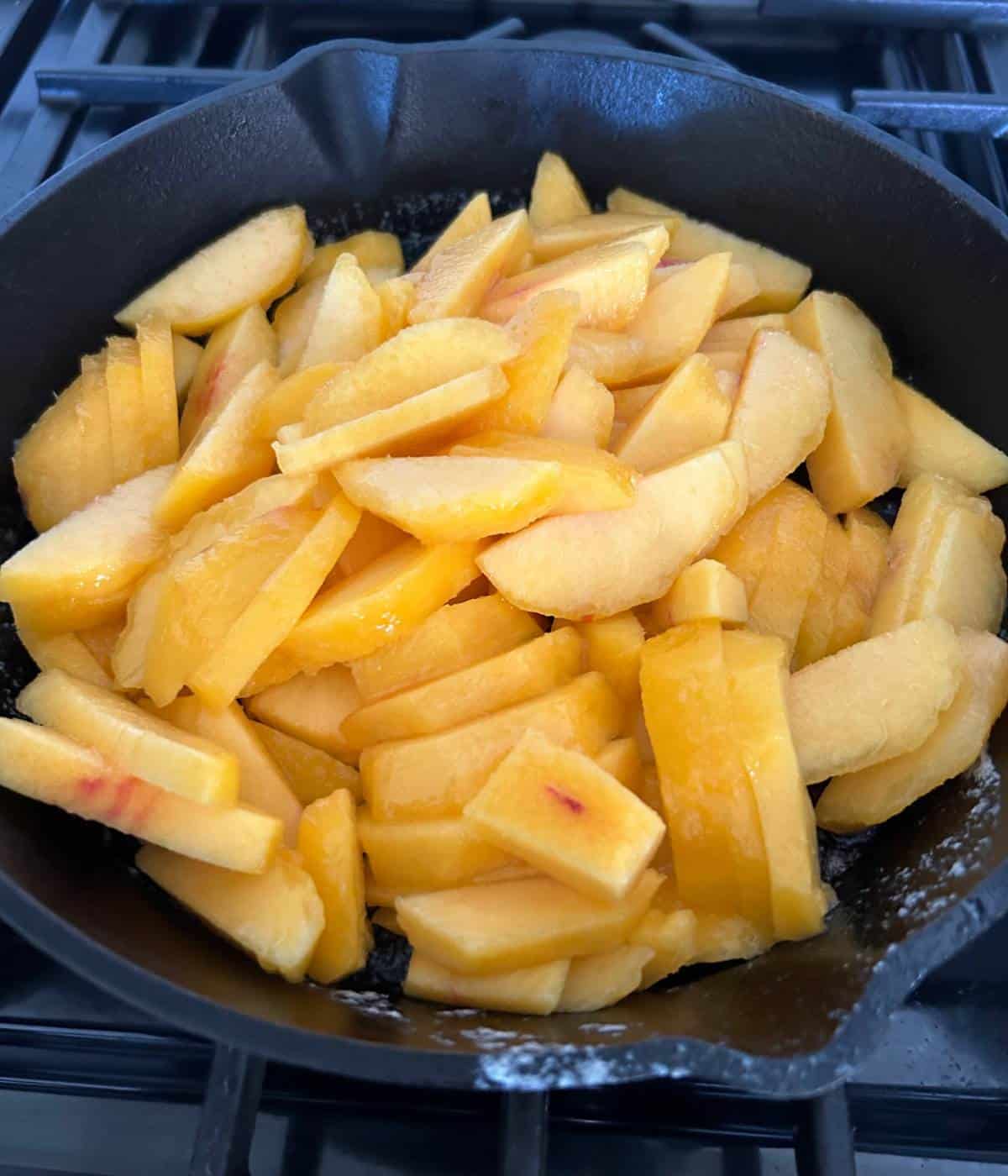 Sliced peaches in cast iron skillet.