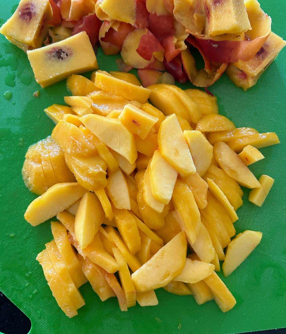 Sliced and peeled peaches on cutting board.