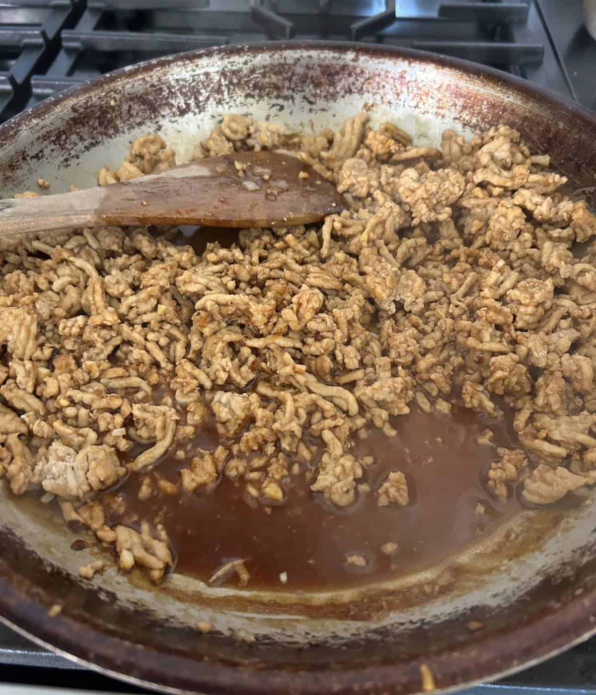 Ground chicken cooking in sauce.