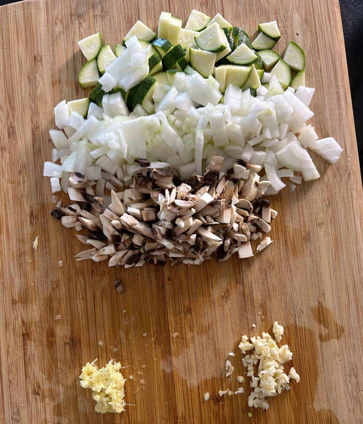 Chopped vegetables and garlic and ginger on cutting board.