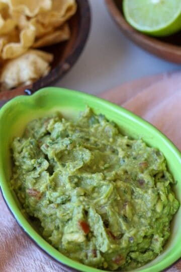 Guacamole in avocado shaped bowl with chips.