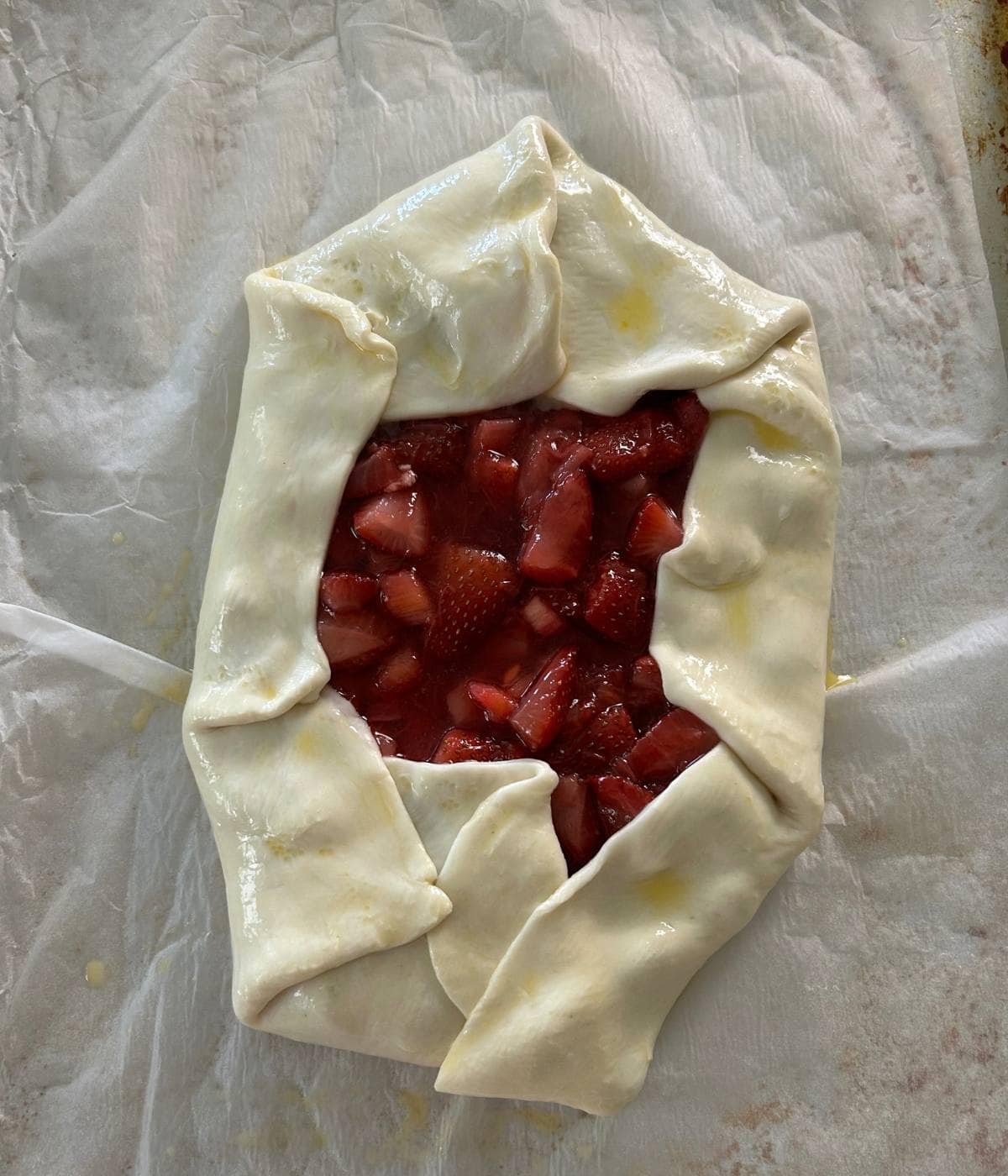 Puff pastry galette wrapped around fruit filling ready to bake.