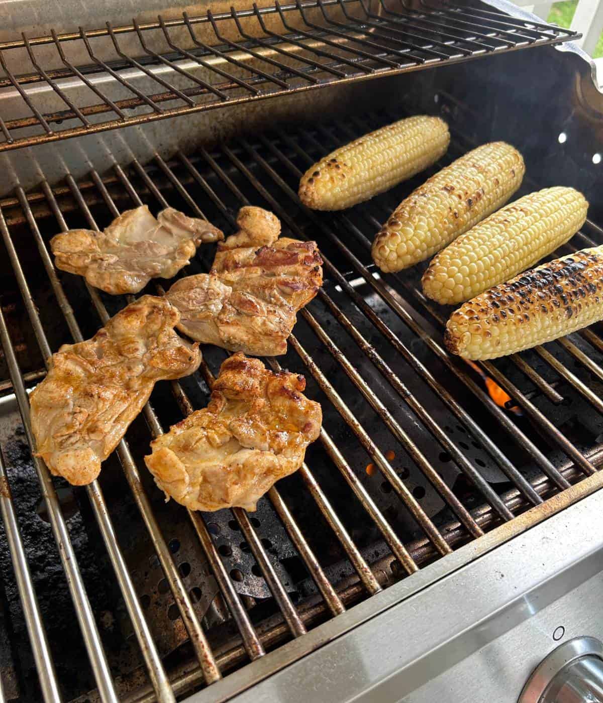 Grilled chicken and corn on grill.