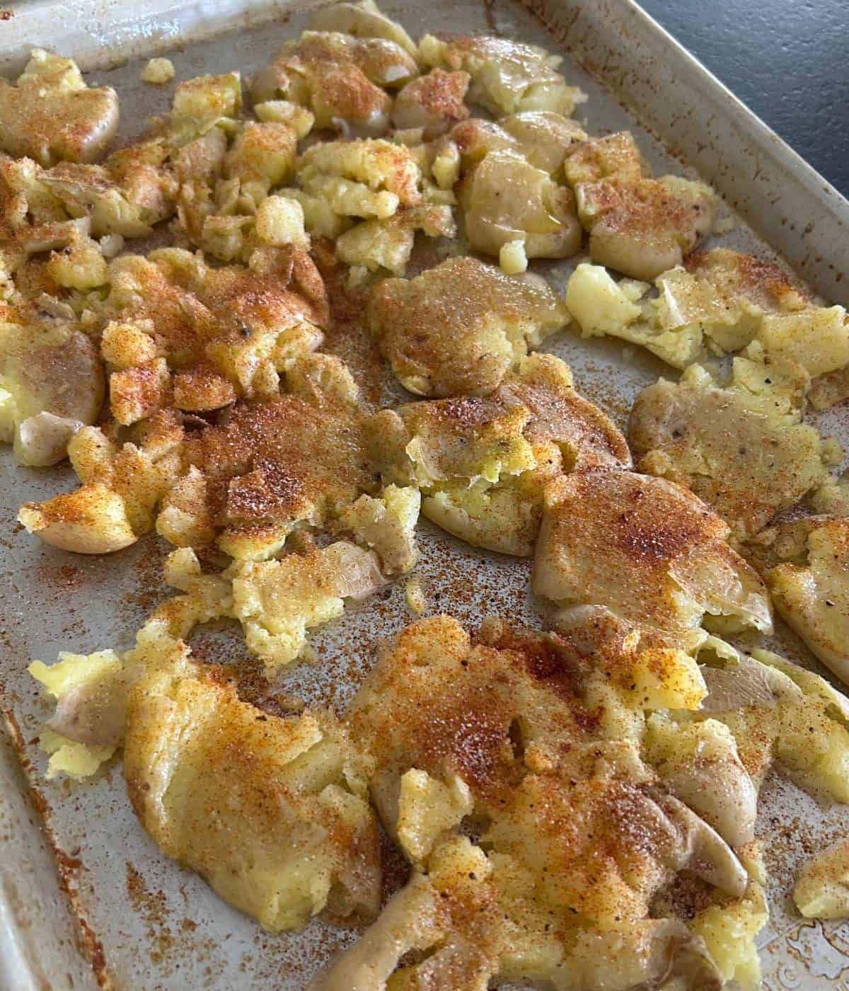 Seasoned smashed potatoes on cookie sheet.