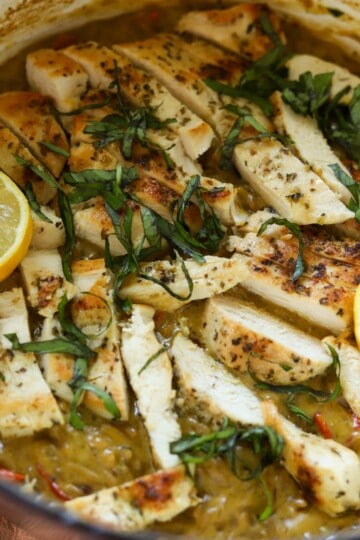 Creamy chicken pesto orzo in pot with lemons.