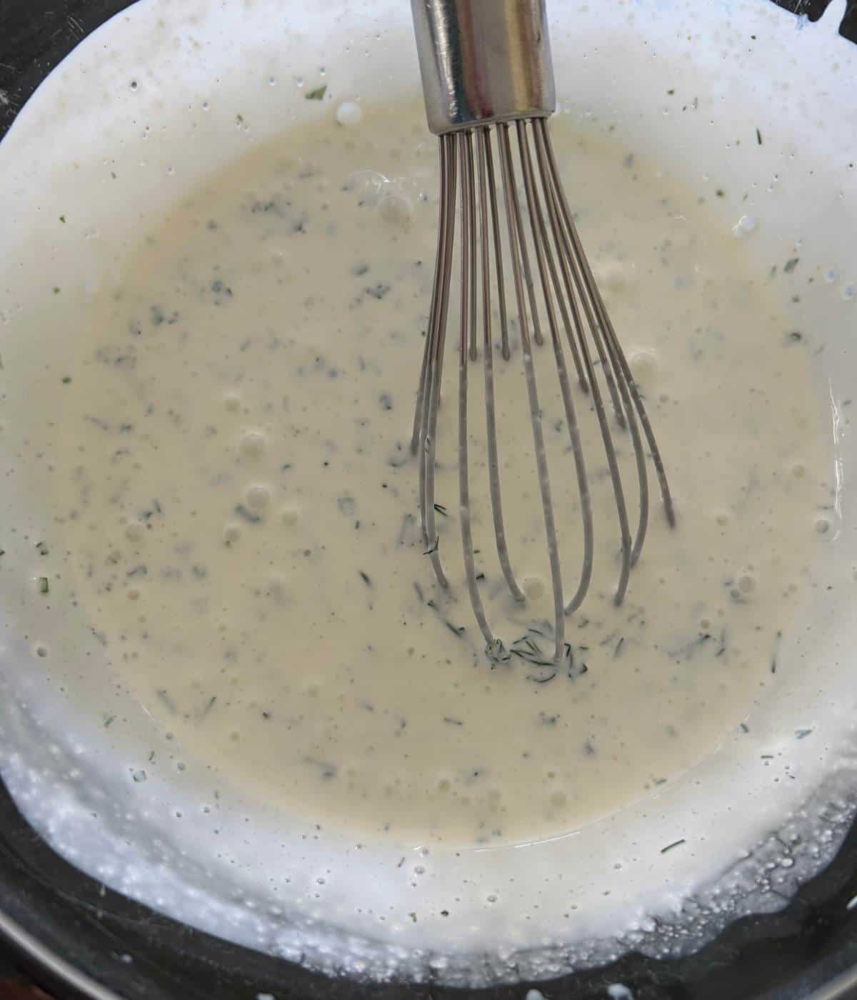Creamy yogurt ranch whisked together in bowl.