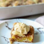 Slice of peach cake on plate with ice cream on top.