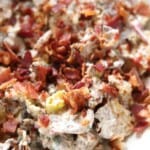Smashed potato salad in bowl topped with bacon.
