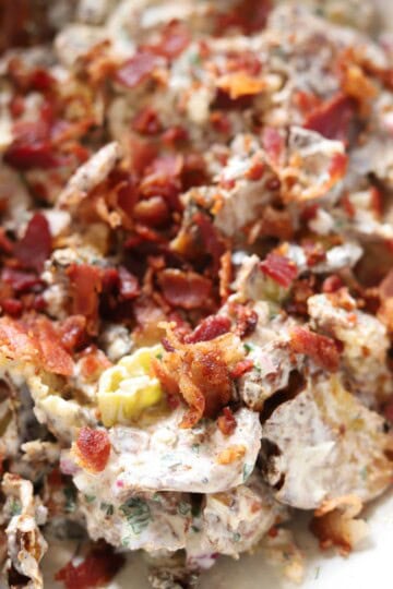 Smashed potato salad in bowl topped with bacon.
