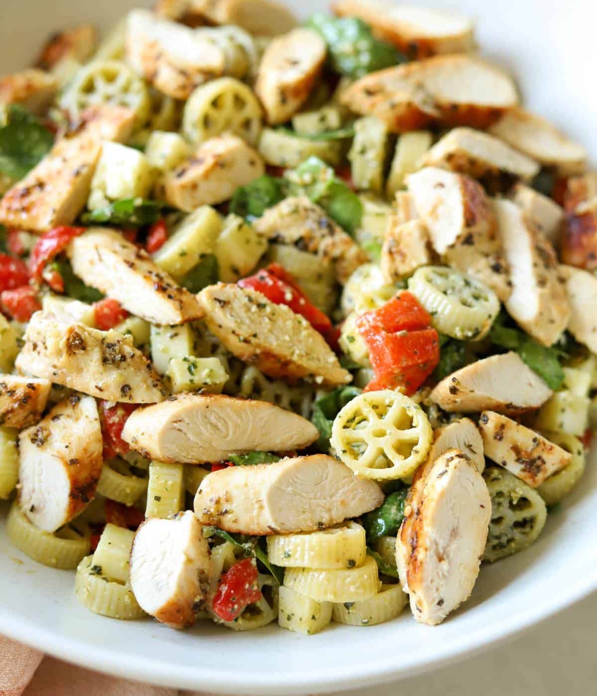 Pesto pasta salad with chicken in bowl.