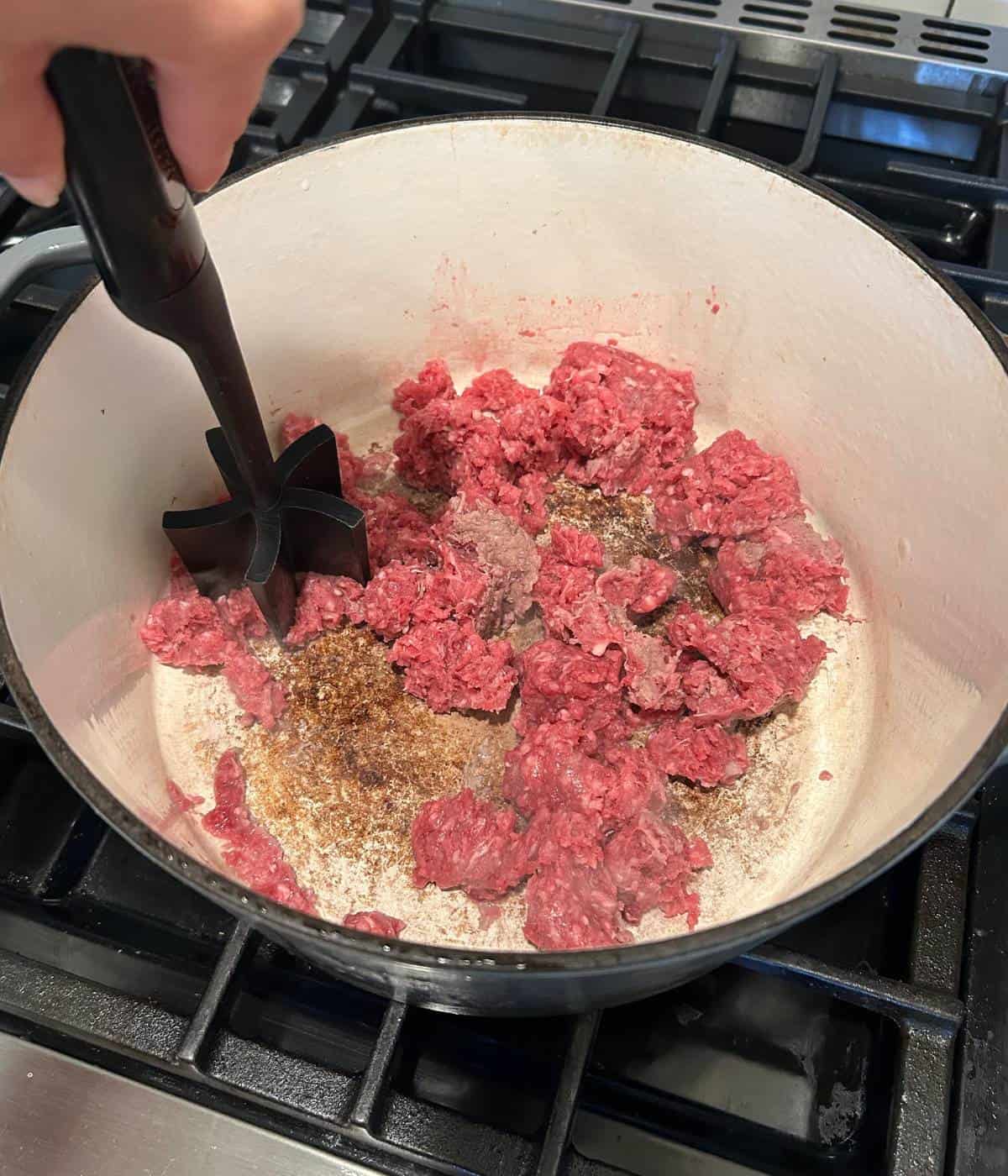 Breaking up ground beef in dutch oven.
