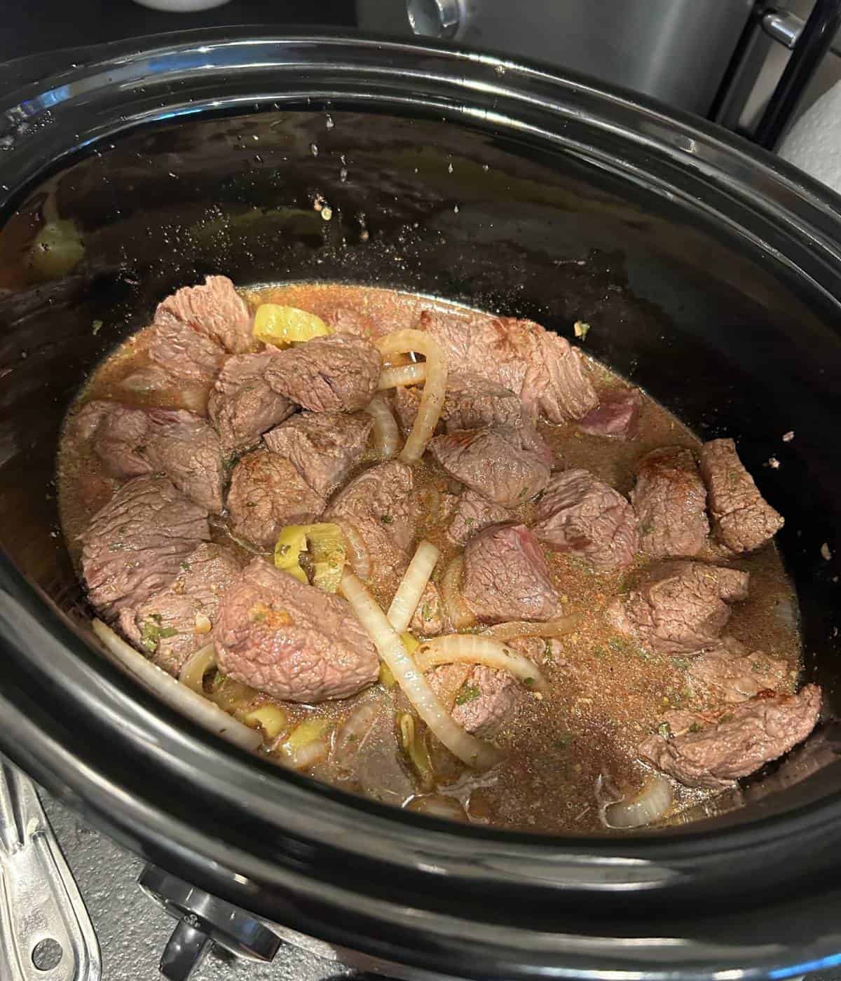 Beef and ingredients in crockpot before cooking.