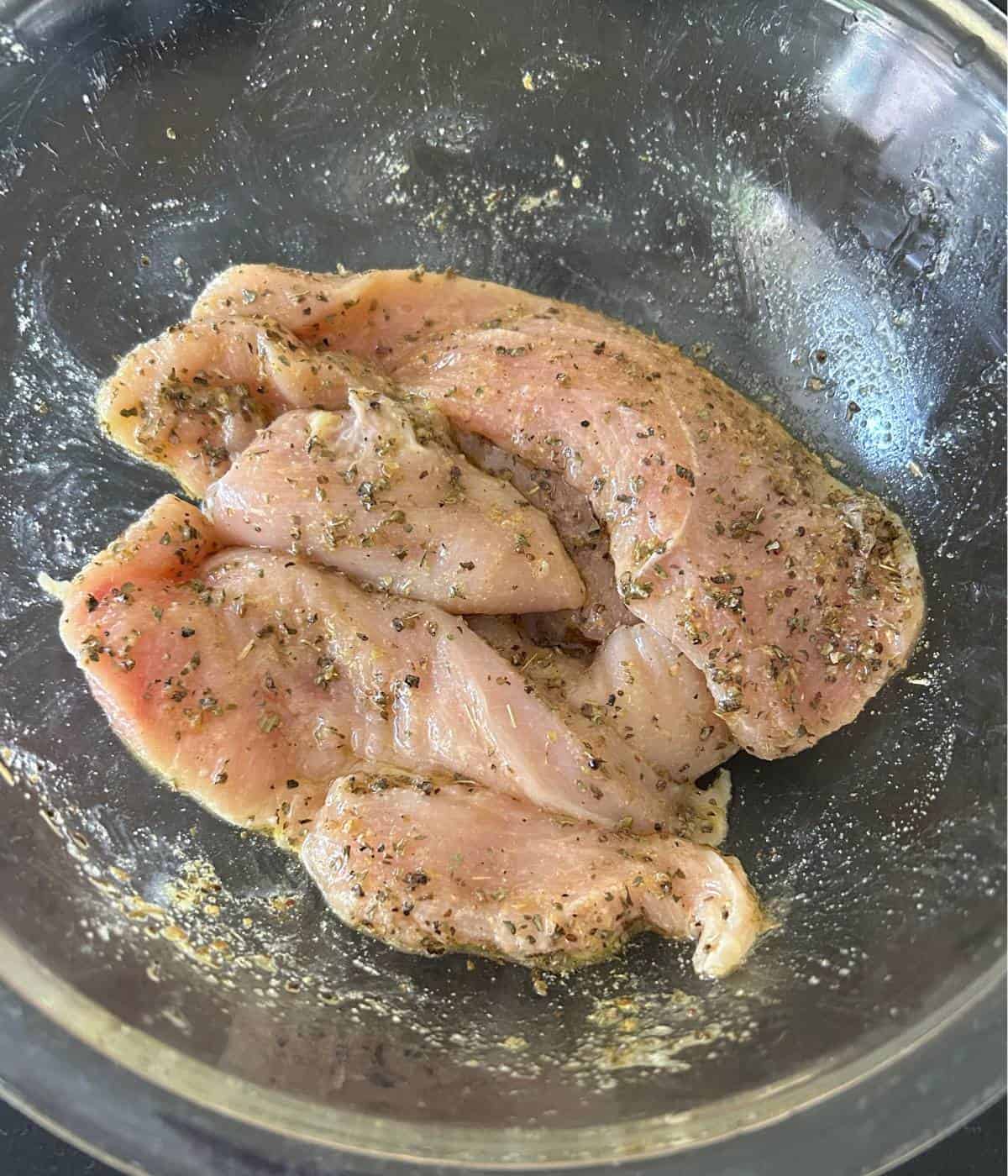 Marinated chicken cutlets in bowl.