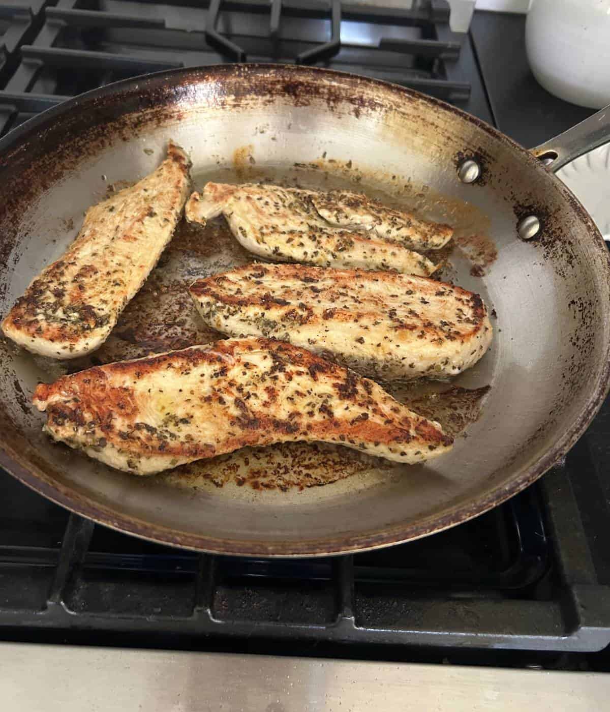 Chicken breast cooking in skillet.