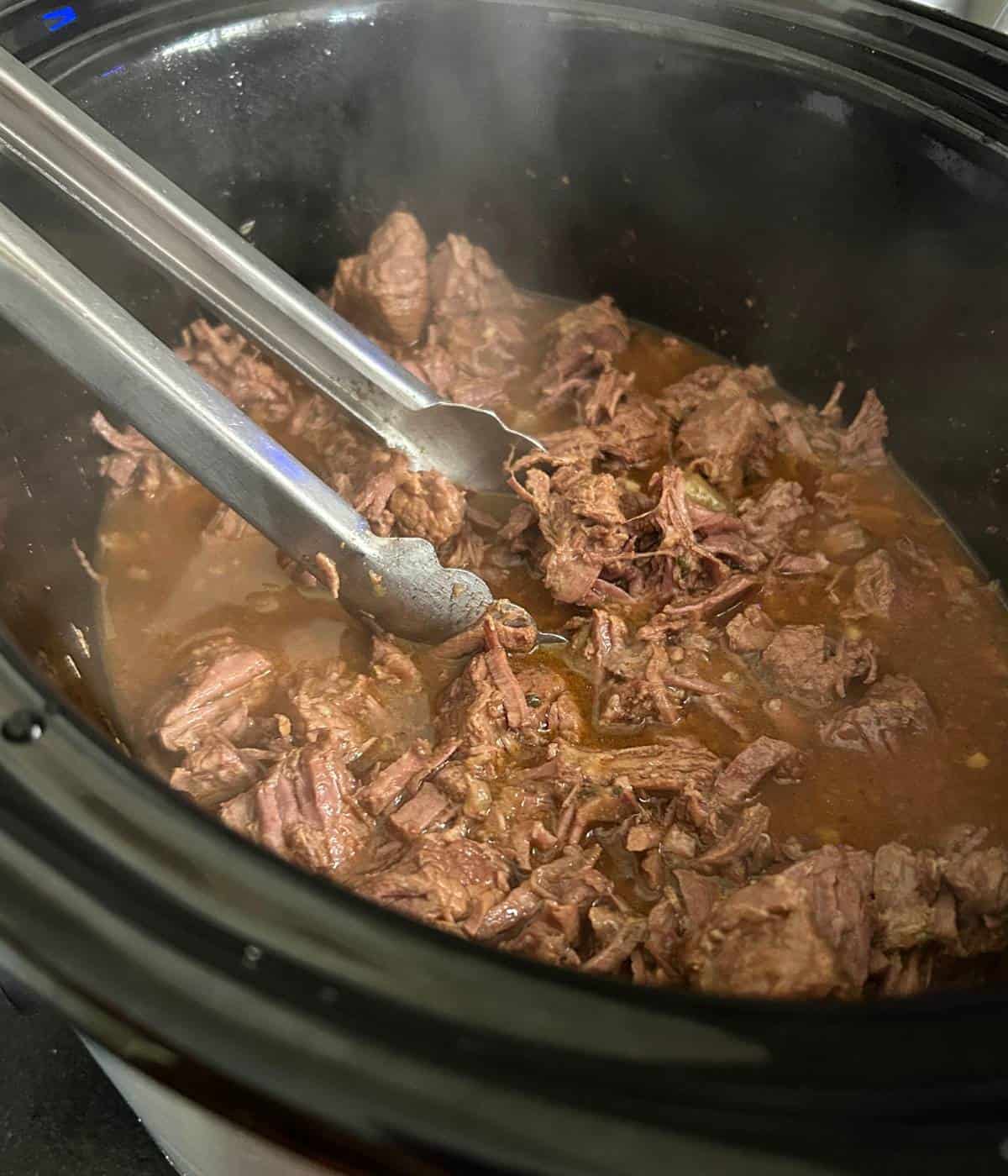 Shredding beef apart in the crockpot.